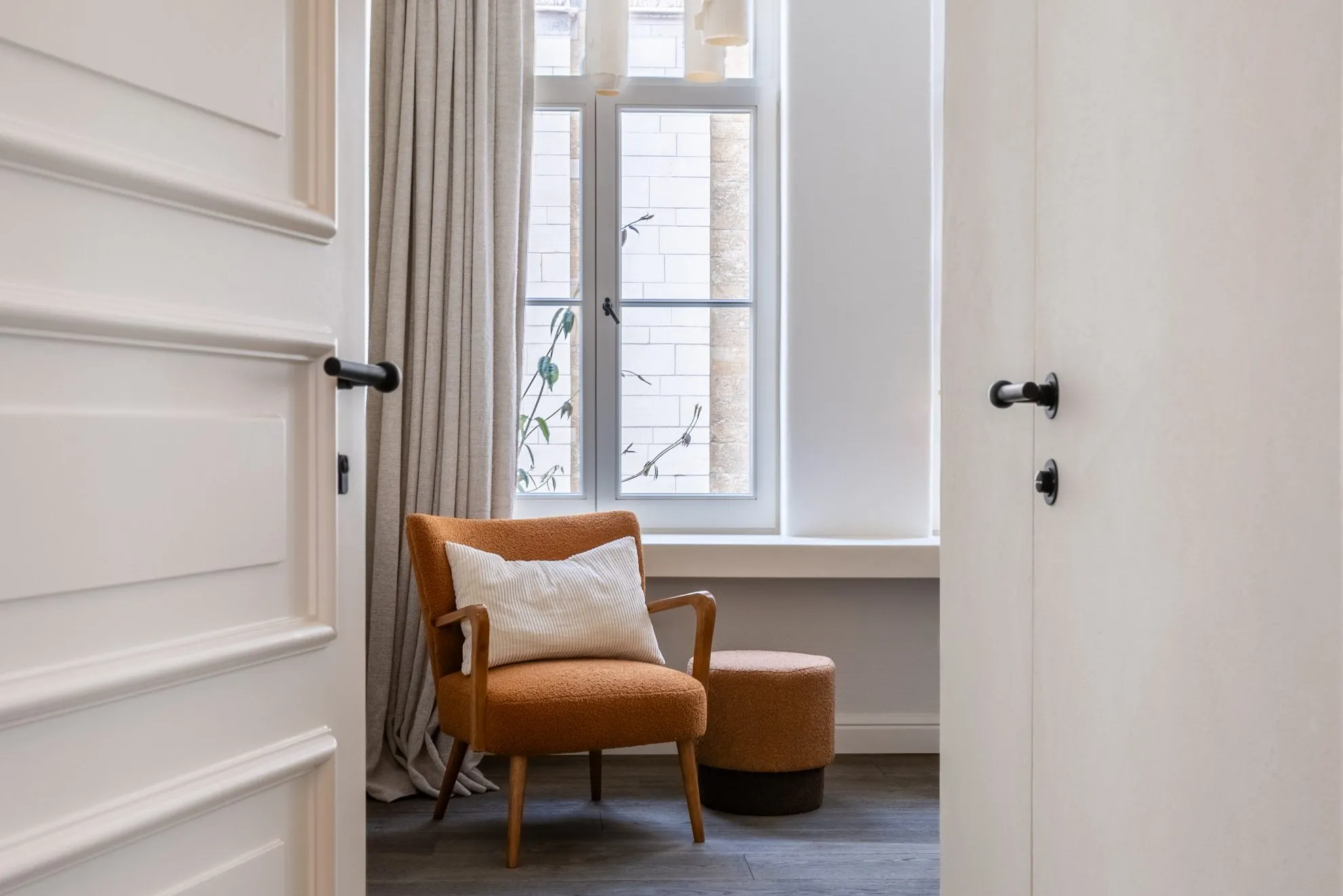 A quiet reading corner with an armchair beside a tall window