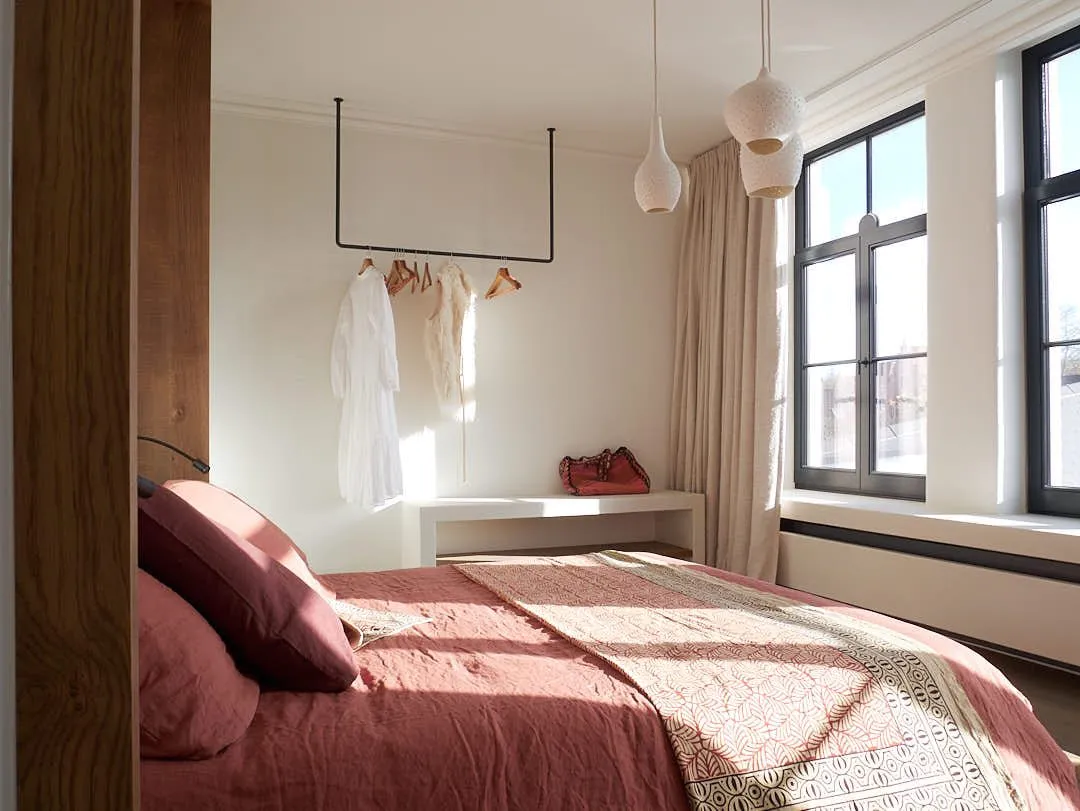 A guest bedroom with linen bedding, handmade porcelain pendant lights and a bright window